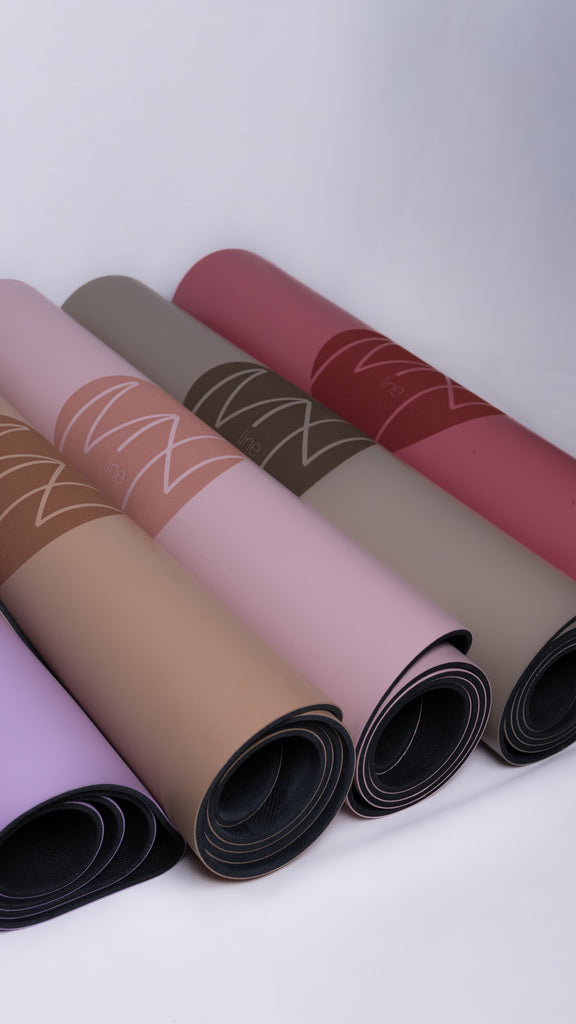 Set of rolled-up yoga mats in various colors on a white background